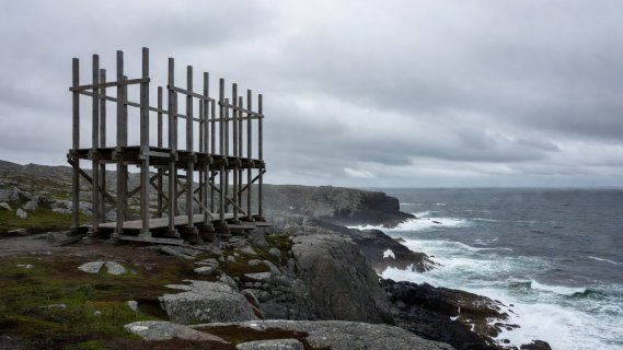 Timber scaffold frame of Steilneset memorial overlooking rocky Arctic coastline